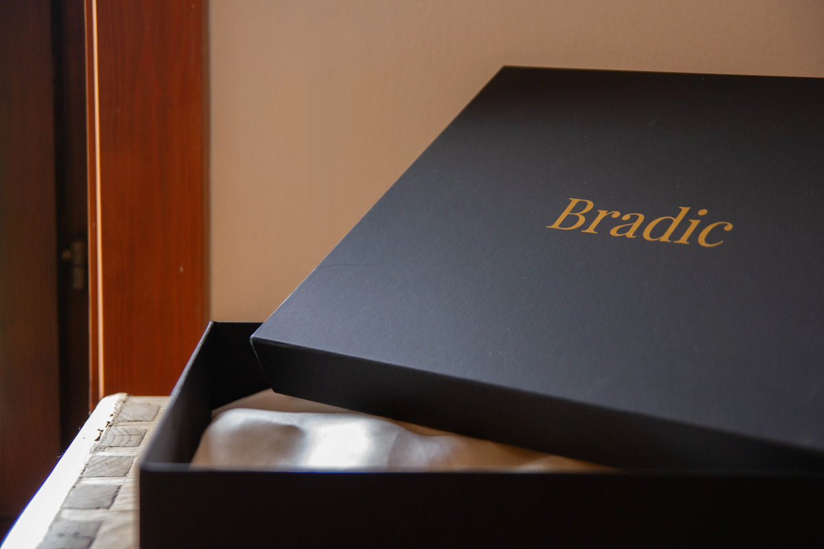 Black box with silk interior and 'Bradic' branding on a wooden surface