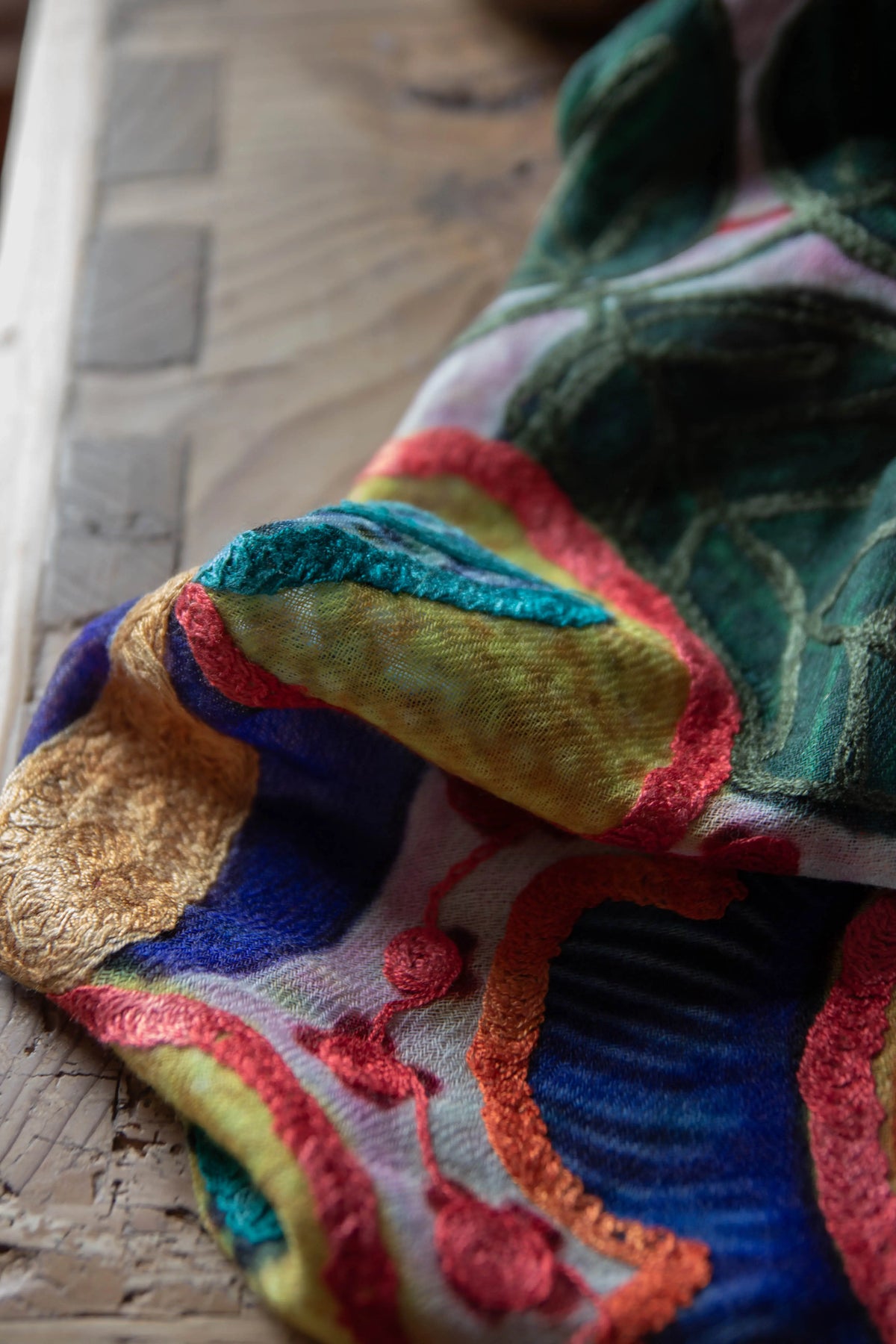 Floral silk-cashmere embroidered fabric on a wooden surface